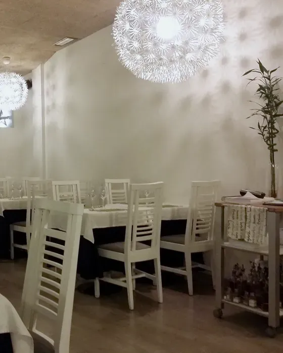 Comedor de El Laurel con lámpara de papel, mesas y sillas blancas
